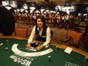 a female dealer sitting in front of a casino table